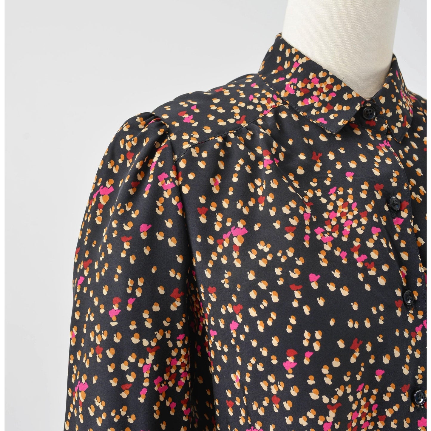 View of shoulder on 70s black spotted blouse. Matte silky fabric. Collared neckline with long puff sleeves.