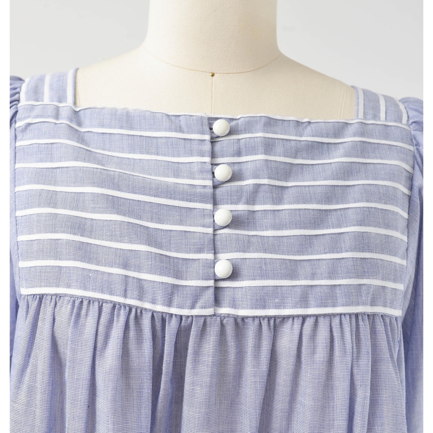 Button closures down neckline on 80s blue and white striped cotton tent dress with puff sleeves. Front view.