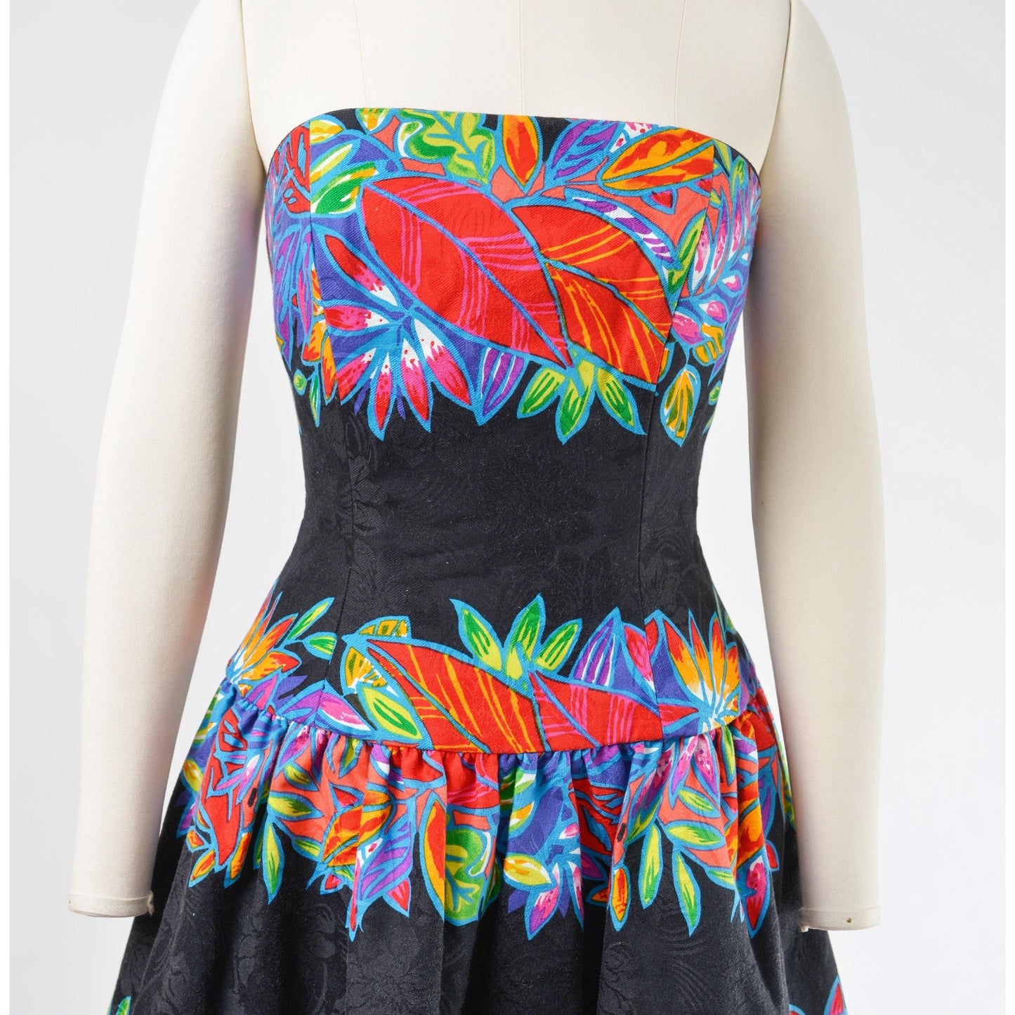 Close up view of bodice on a vintage 1980's tropical leaf print cotton dress. Strapless with drop waist.
