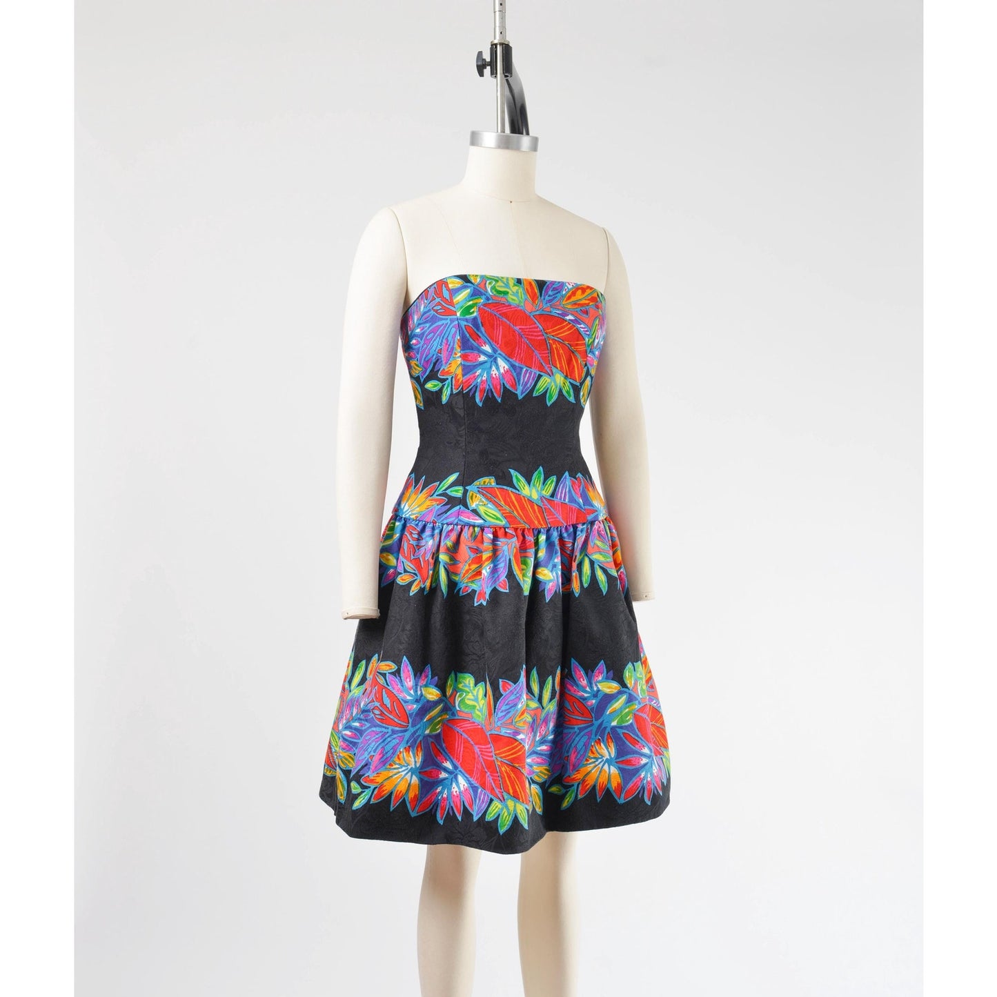 Side view of a vintage 1980's tropical leaf print cotton dress. Strapless with drop waist.