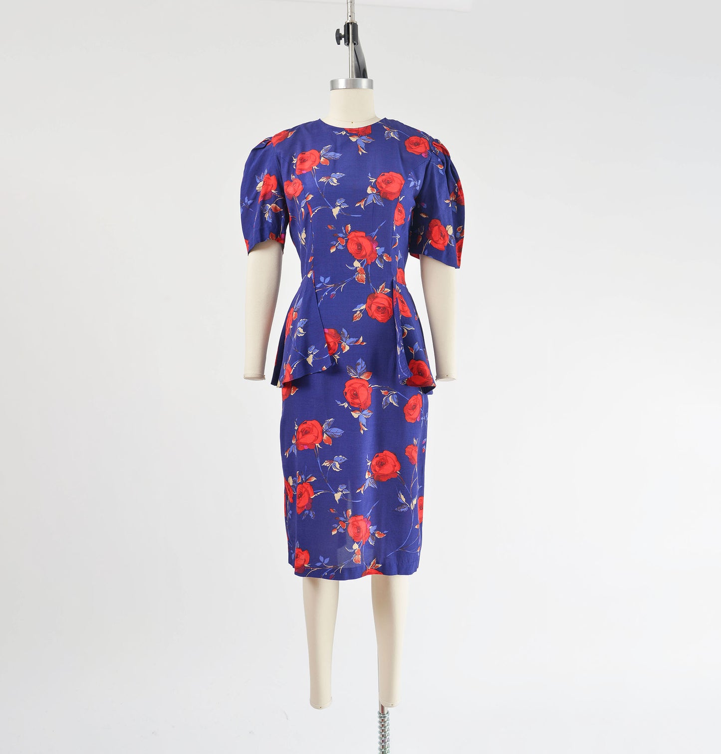 Full front view of vintage 1980s purple and red floral print midi dress. Peplum waist with puff sleeves.