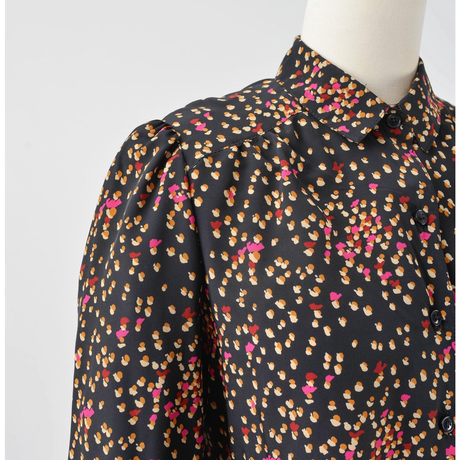 View of shoulder on 70s black spotted blouse. Matte silky fabric. Collared neckline with long puff sleeves. 