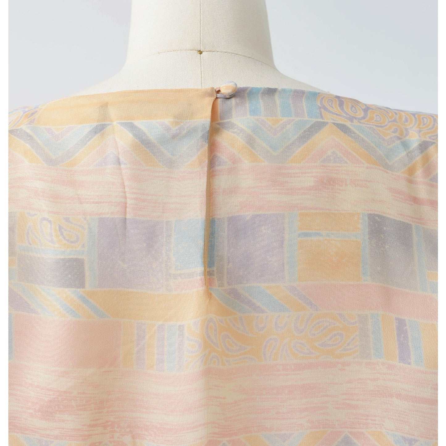 View of rear button closure at back neck on the 70s pastel geometric sheer chiffon blouson midi dress with tie belt. 