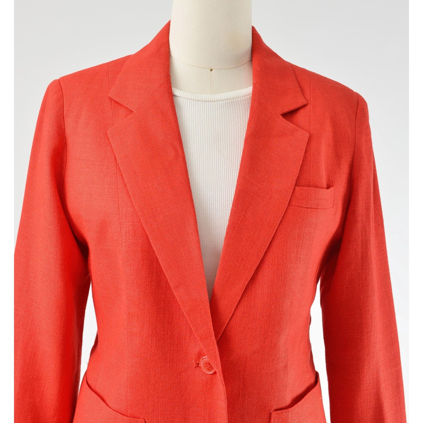 Close up view of neckline on Vintage 1970s red linen and rayon blend blazer. Fitted silhouette. Two button closures with large hip pockets. 