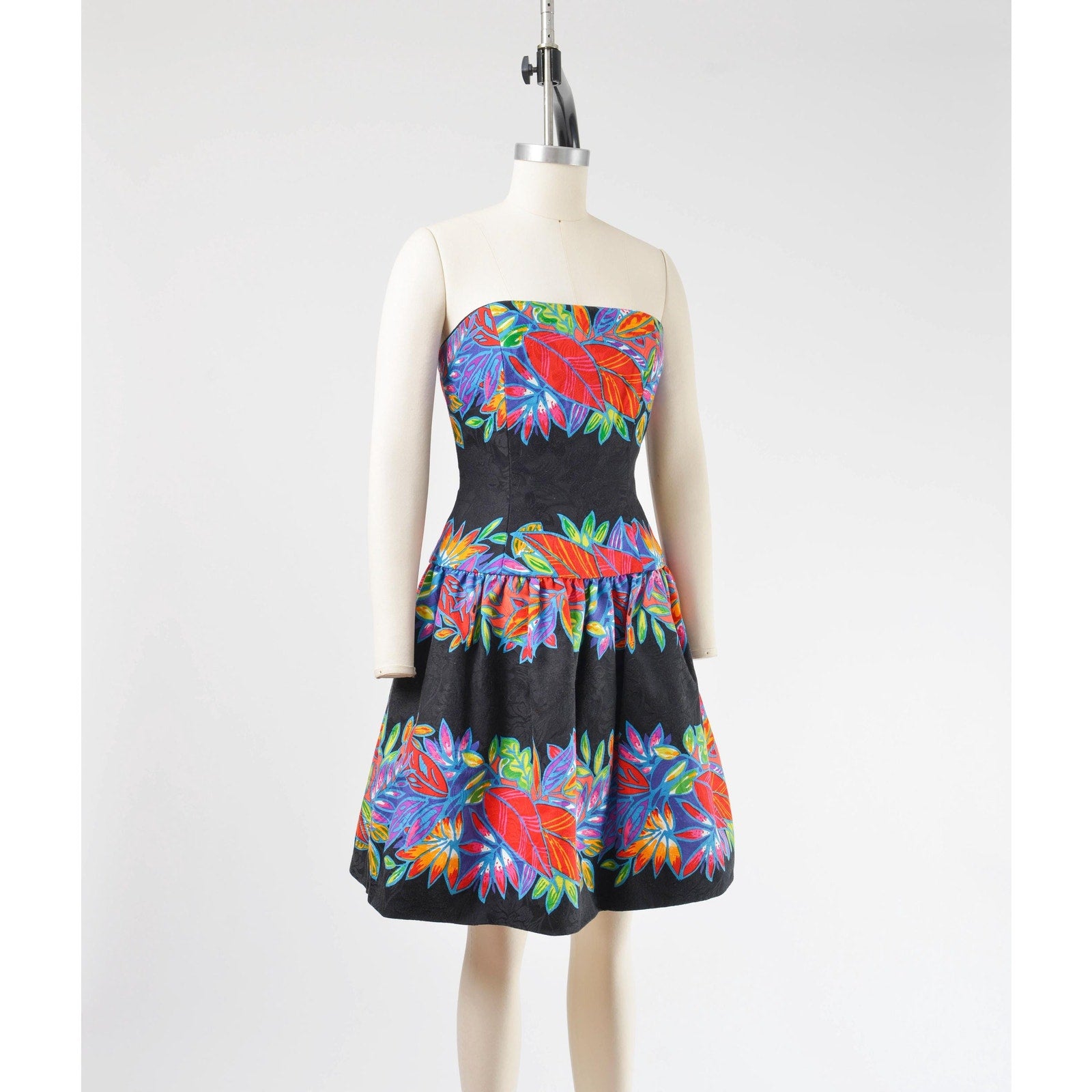 Side view of a vintage 1980's tropical leaf print cotton dress. Strapless with drop waist. 